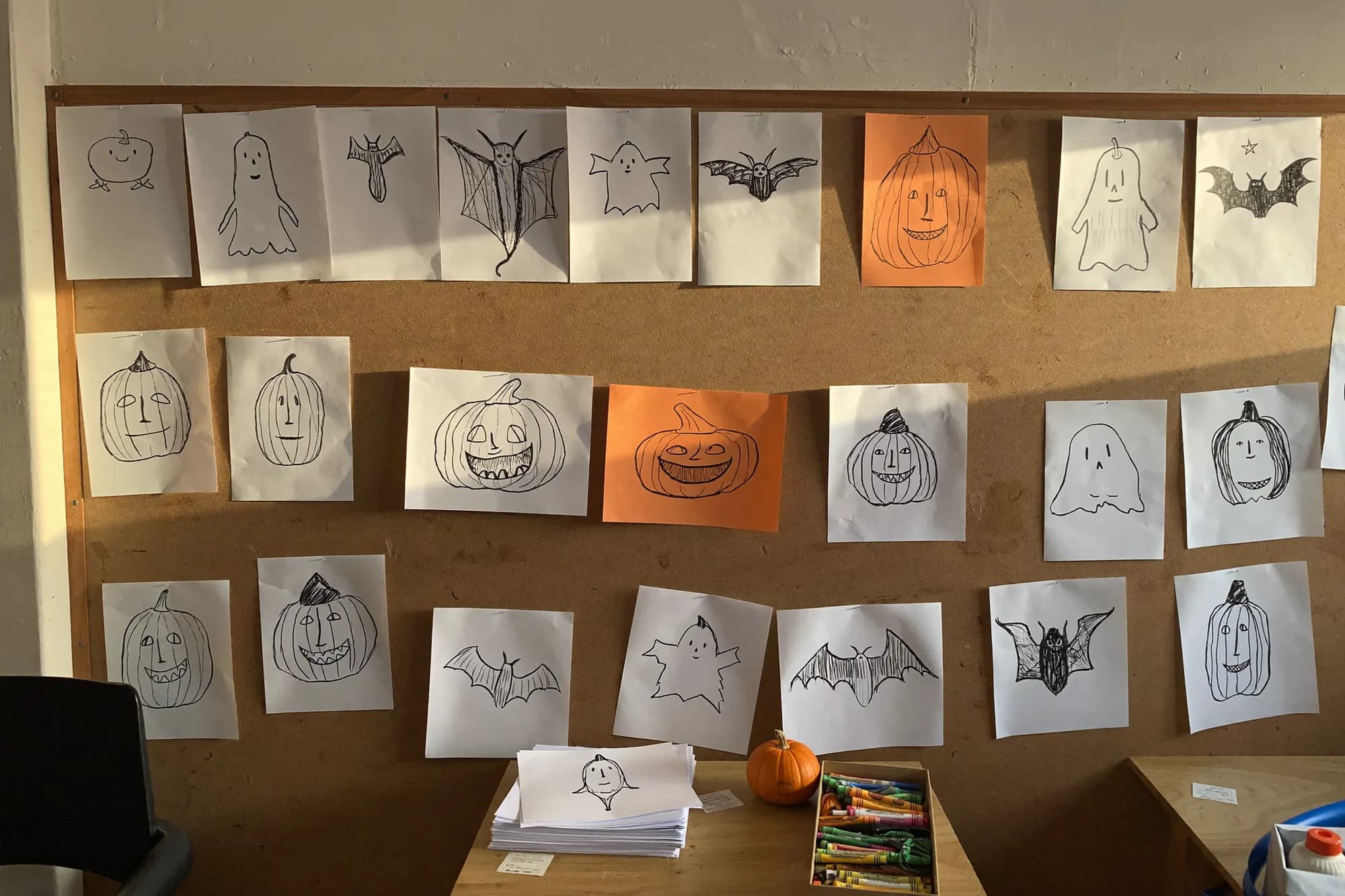 A preschool display wall covered in children’s drawings of ghosts, bats and pumpkins